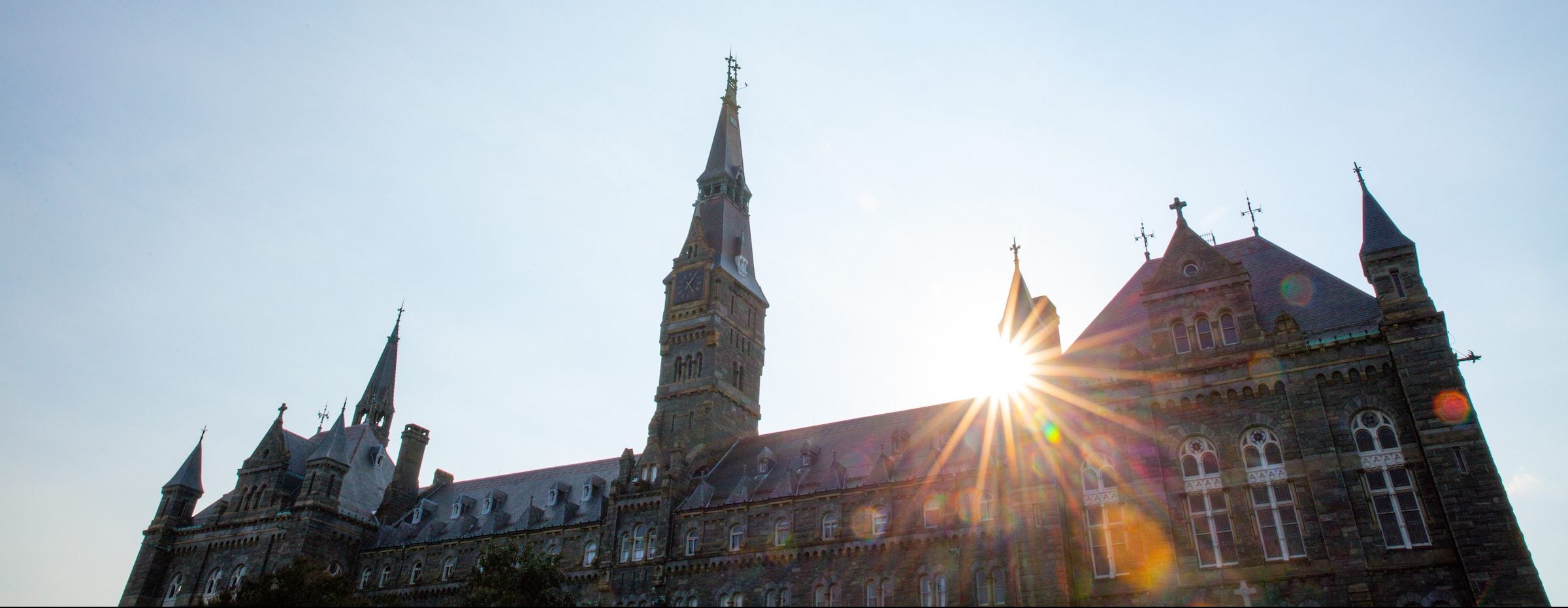 Sun shining behind Healy Hall at sunset