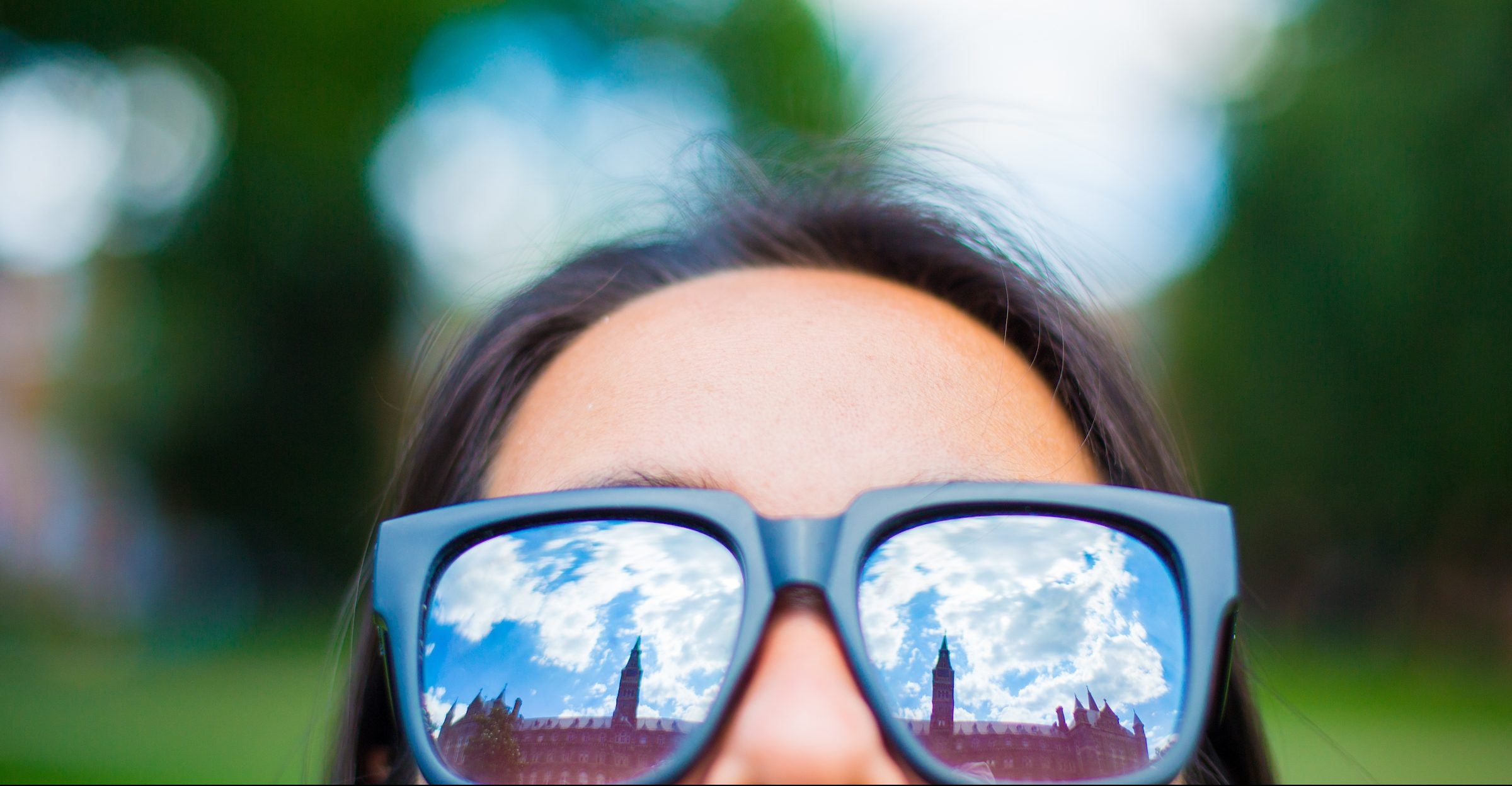 Healy Hall is reflected from a student's sunglasses