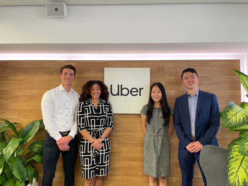 Four Georgetown students stand in front of a sign that says "Uber" at the company's office in Madrid, Spain