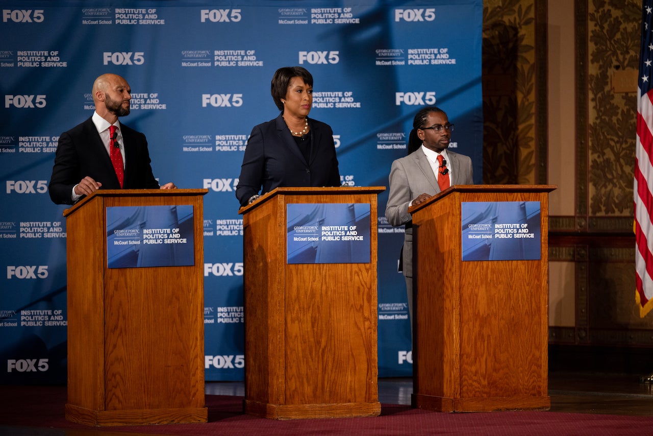 An image of three of the Democratic candidates running for mayor of DC behind three podiums in Gaston Hall during a live televised debate.