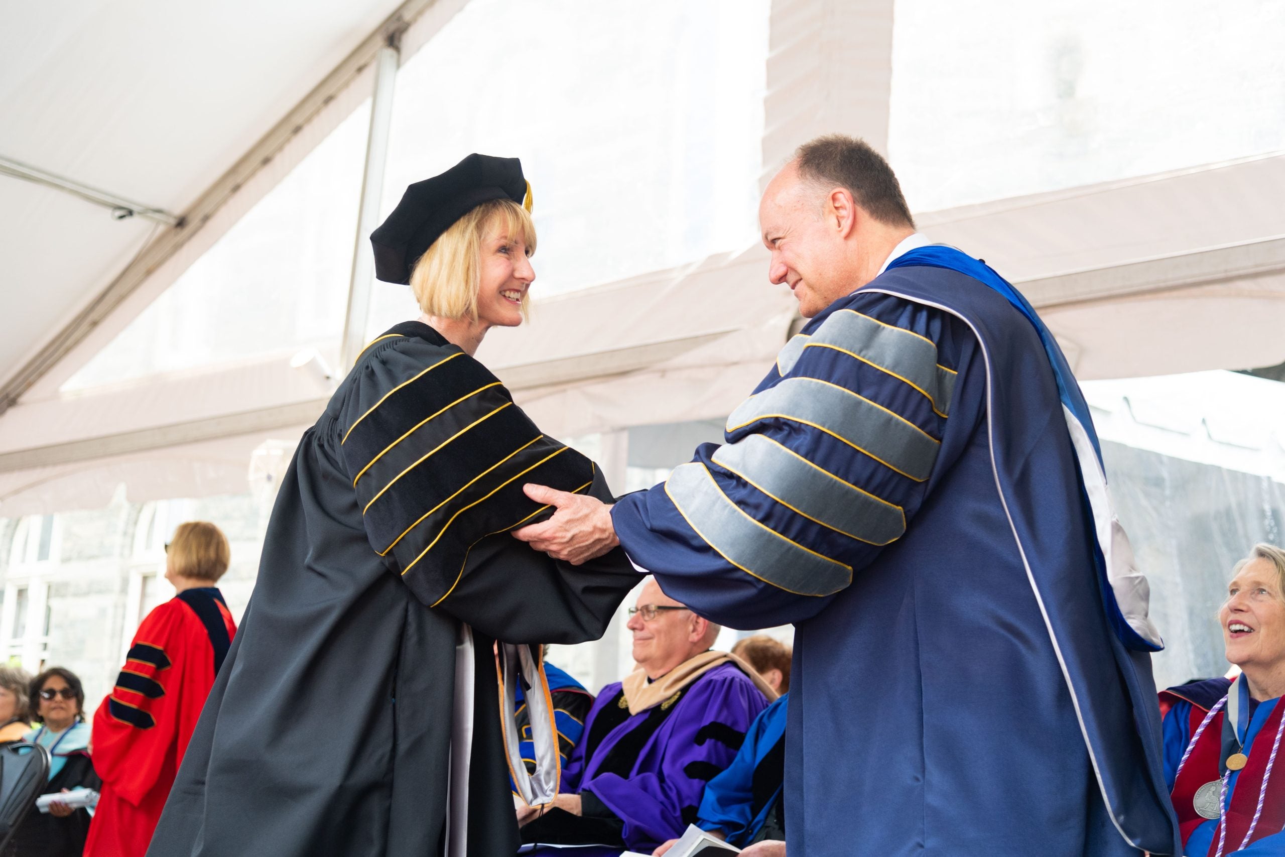 President DeGioia and a Ph.D. graduate shaking hands on stage