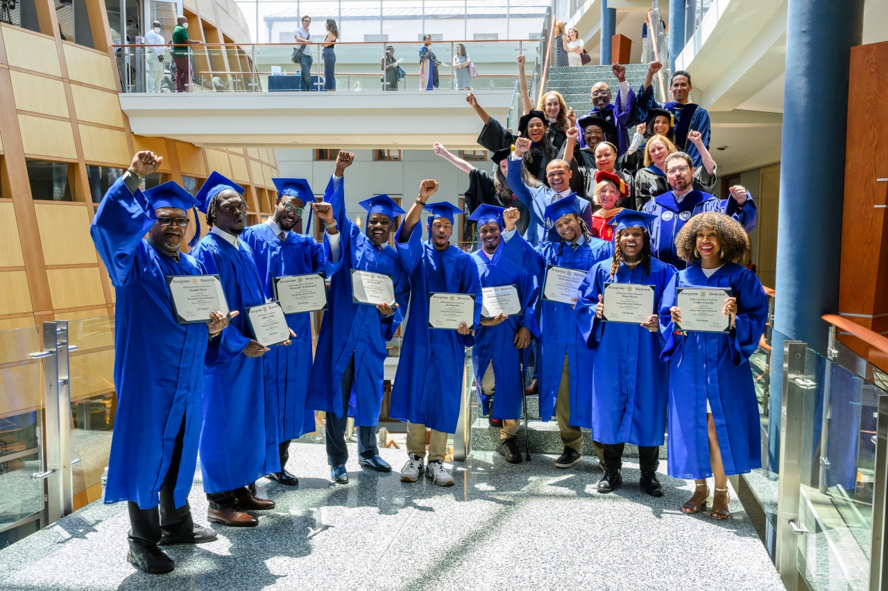 An image of graduates from the Pivot Program wearing blue cap and gowns.