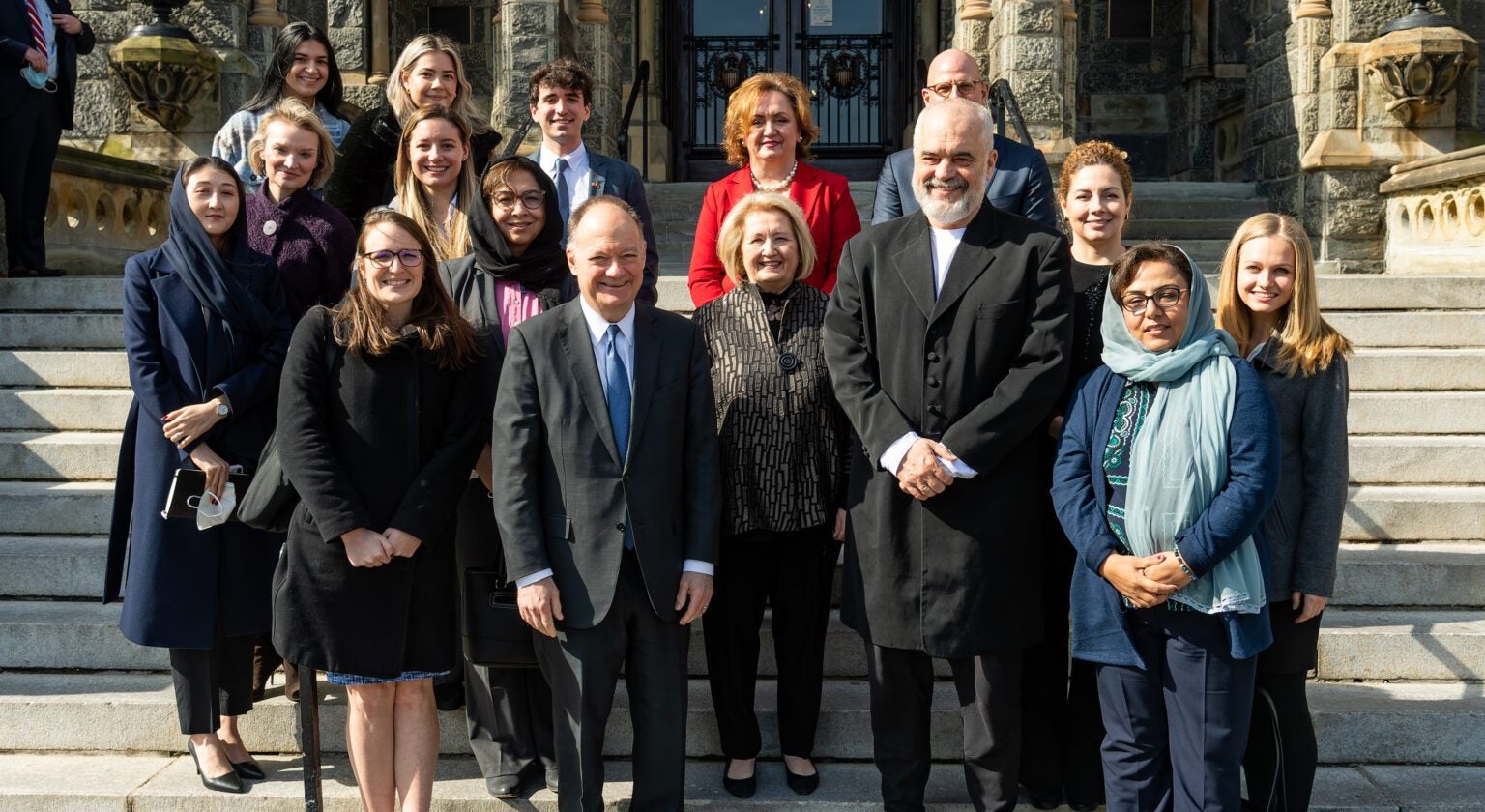 President DeGioia stands with a group of dignitaries in front of Healy Hall