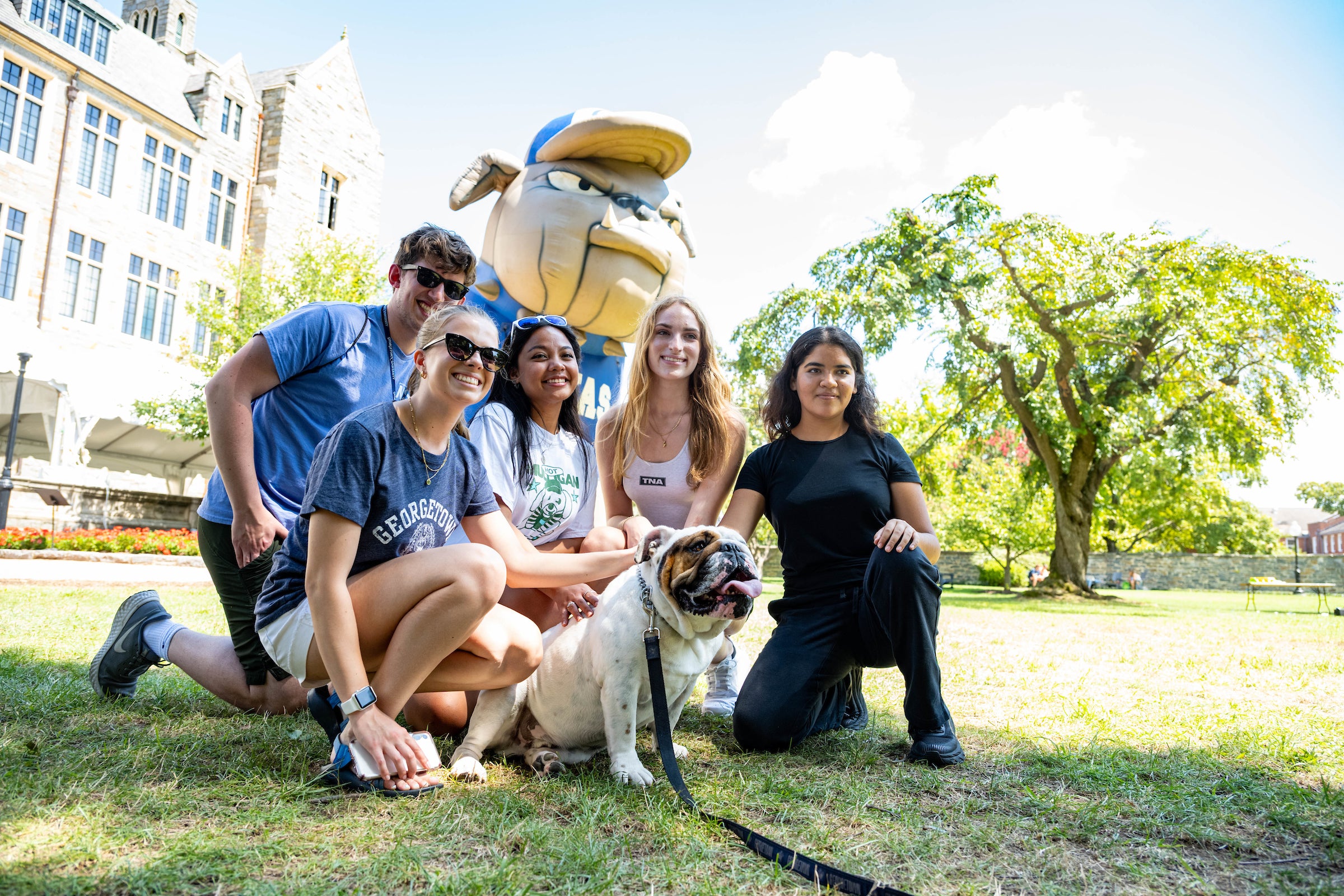 Students kneel in front of a blow-up Jack the Bulldog with the real Jack the Bulldog