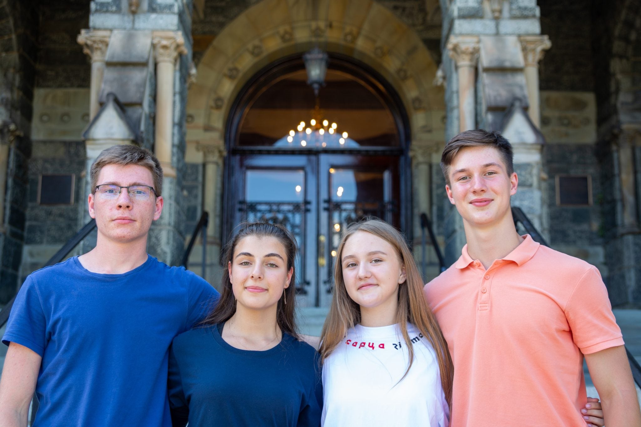 Four students in Georgetown's new scholarship for students impacted by the war in Ukraine pose outside Georgetown's Healy Hall on its main campus.