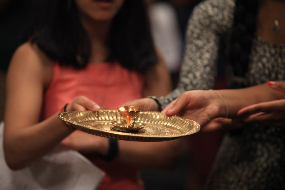 Students hold a gold ghee-lamp in the Hindu ritual of aarti, which asks God to bless the devotee's heart and mind with love and compassion.