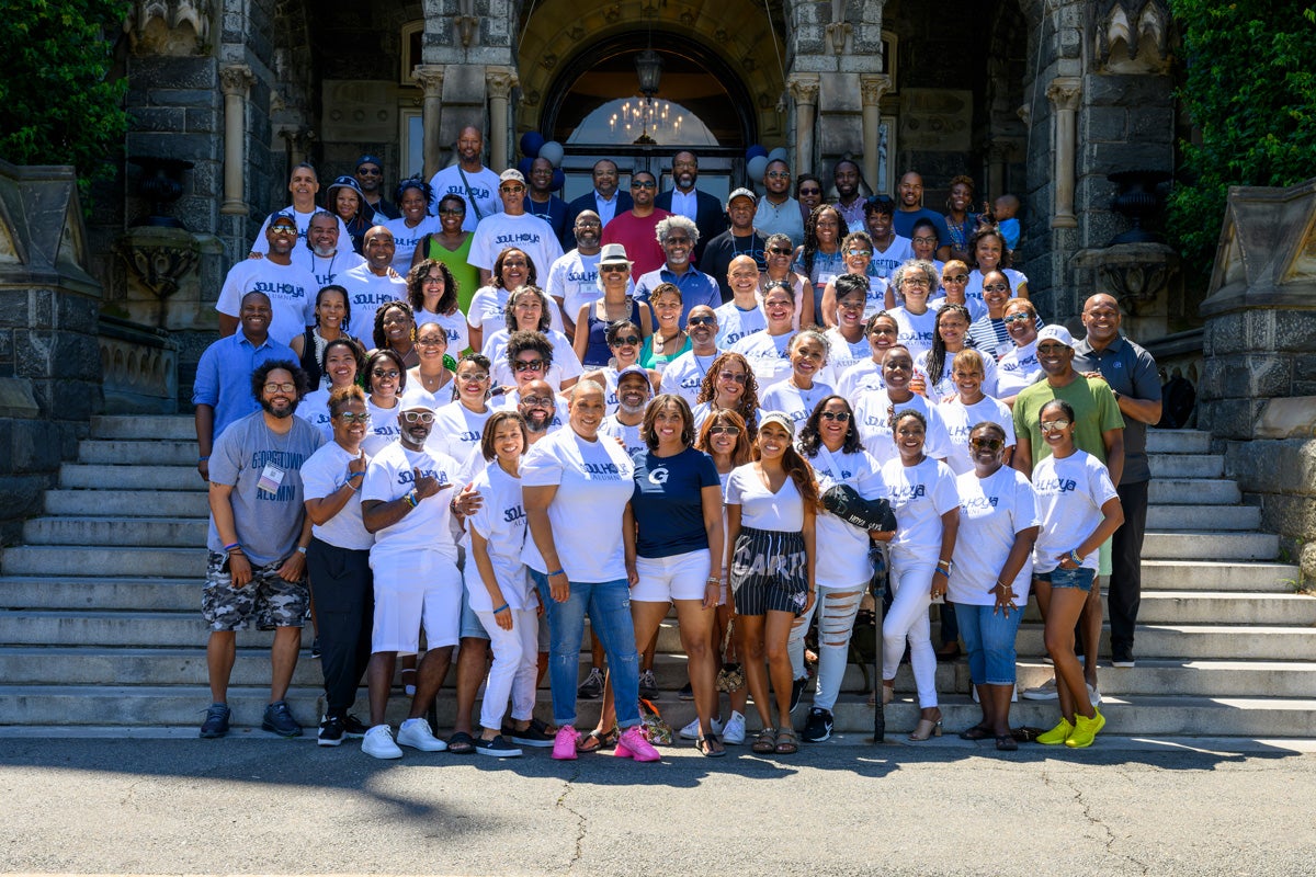 Members of the organizes the Soul Hoyas pose for a picture on the steps of Healy Hall during their annual reunion event. Many of the group members wear white T-shirts that say, "Soul Hoya Alumni"