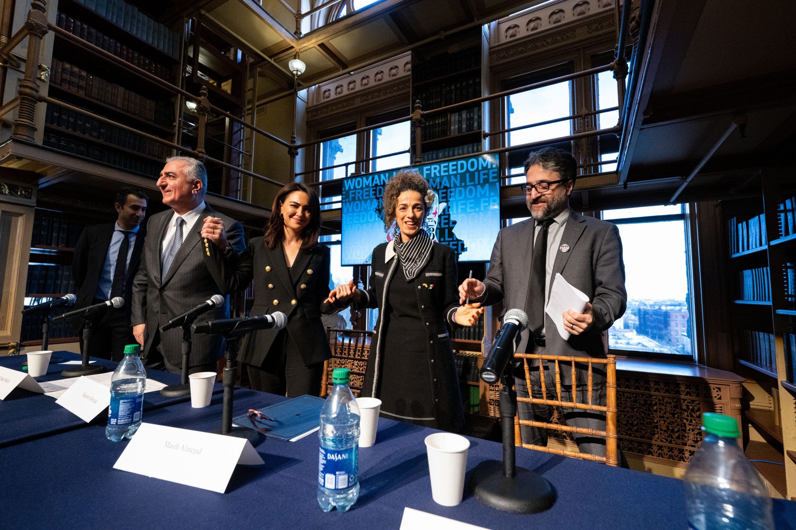 From left: H.E. Reza Pahlavi, Nazanin Boniadi, Masih Alinejad, Dr. Hamed Esmaeilion. The group holds hands as they pose in Riggs Library.