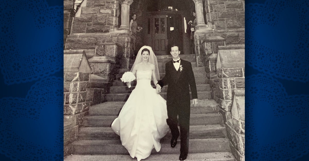 Black and white photo of Norah O'Donnell (C'95, G'03) wearing a wedding dress and Geoff Tracy (C'95) in a tuxedo on the steps of Healy Hall.