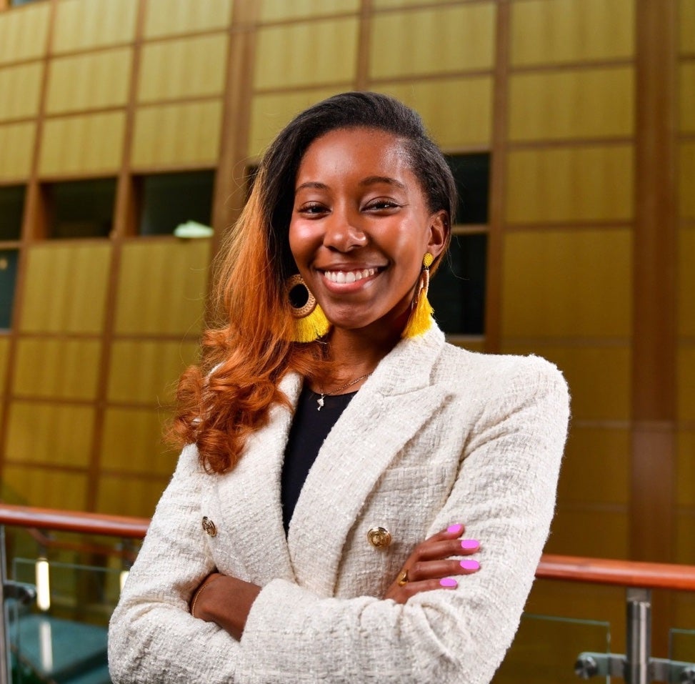 Kilandra Bass (MBA'24), wearing business attire, smiles with crossed arms in the MSB.