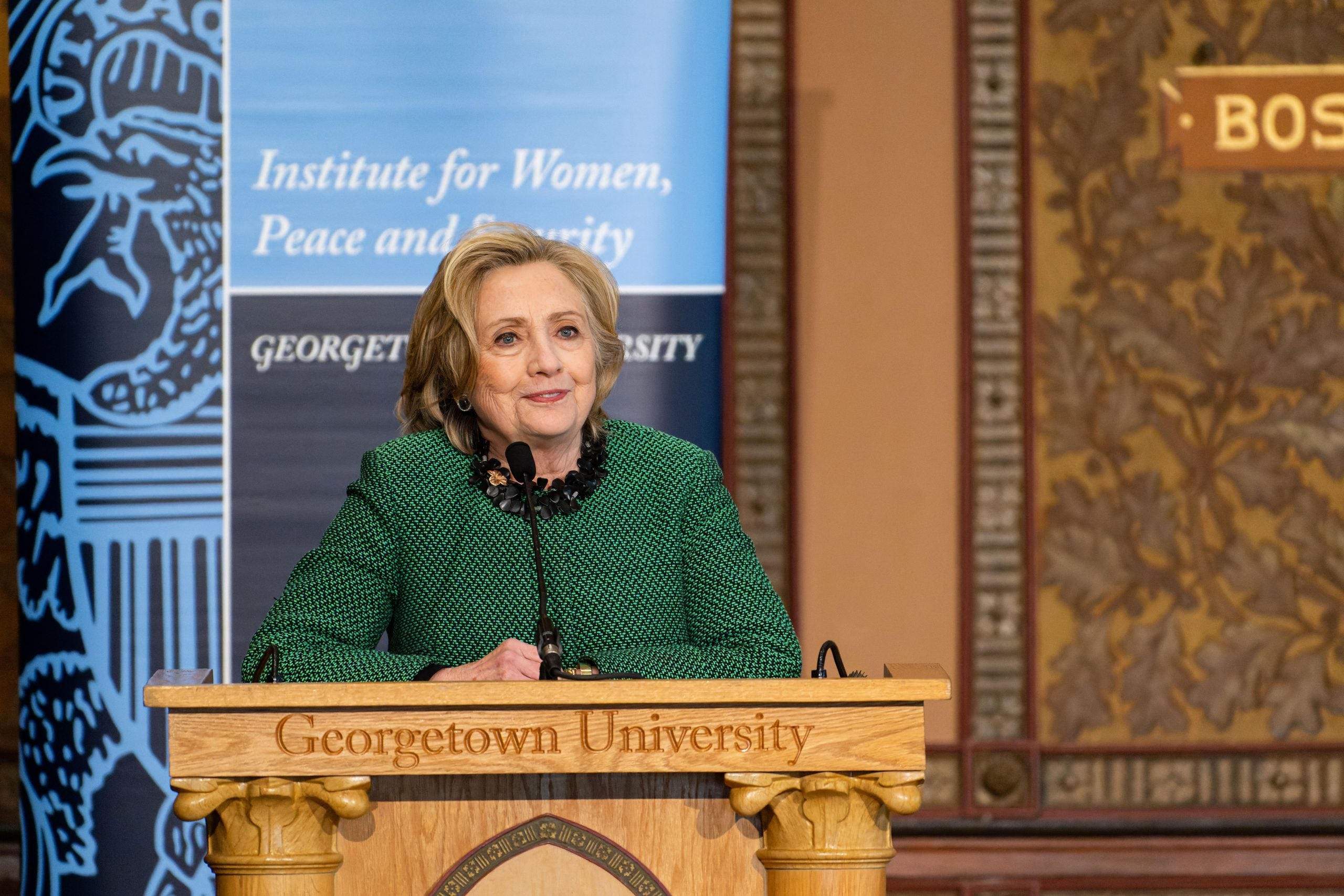 Hillary Clinton speaks at podium in Gaston Hall.