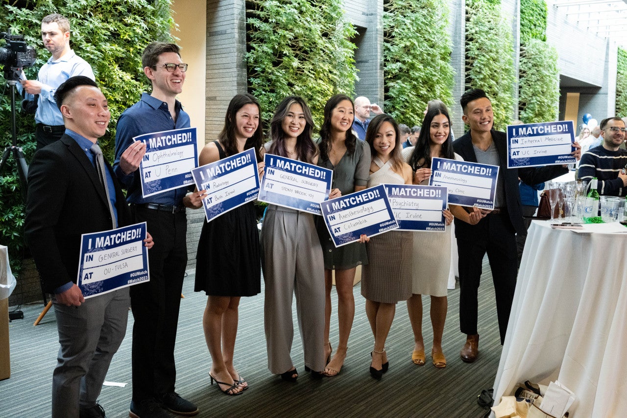 Students pose with signs that indicate the medical school they matched to in the HFSC.