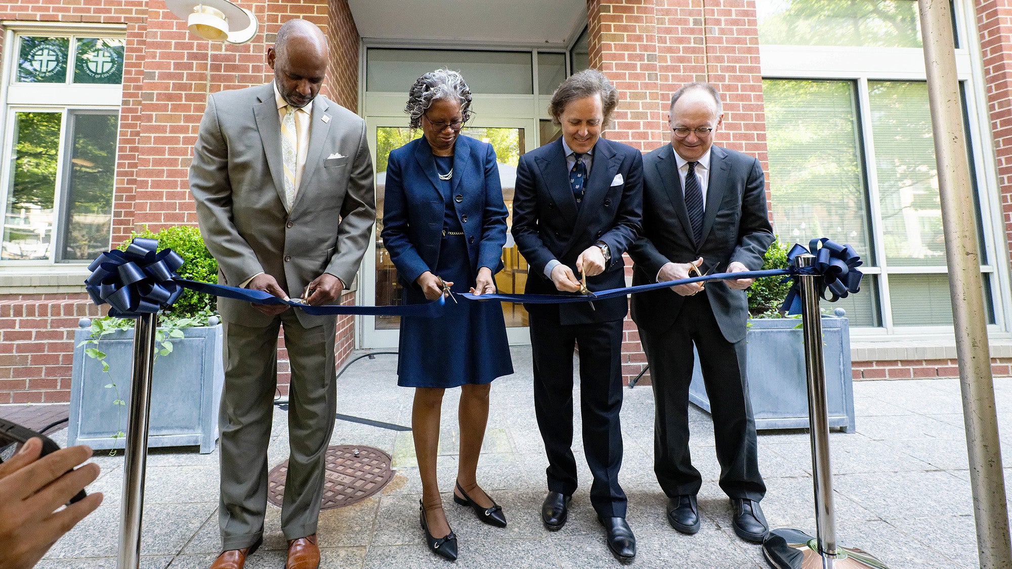 Cutting the ceremonial ribbon to officially open the Ralph Lauren Center are (l to r) Wayne Turnage, D.C.'s Deputy Mayor for Health and Human Services; Lucile Adams-Campbell, PhD, founding director of the Ralph Lauren Center; David Lauren, son of Ralph Lauren and president of the Ralph Lauren Corporate Foundation; and Georgetown University President John J. DeGioia.