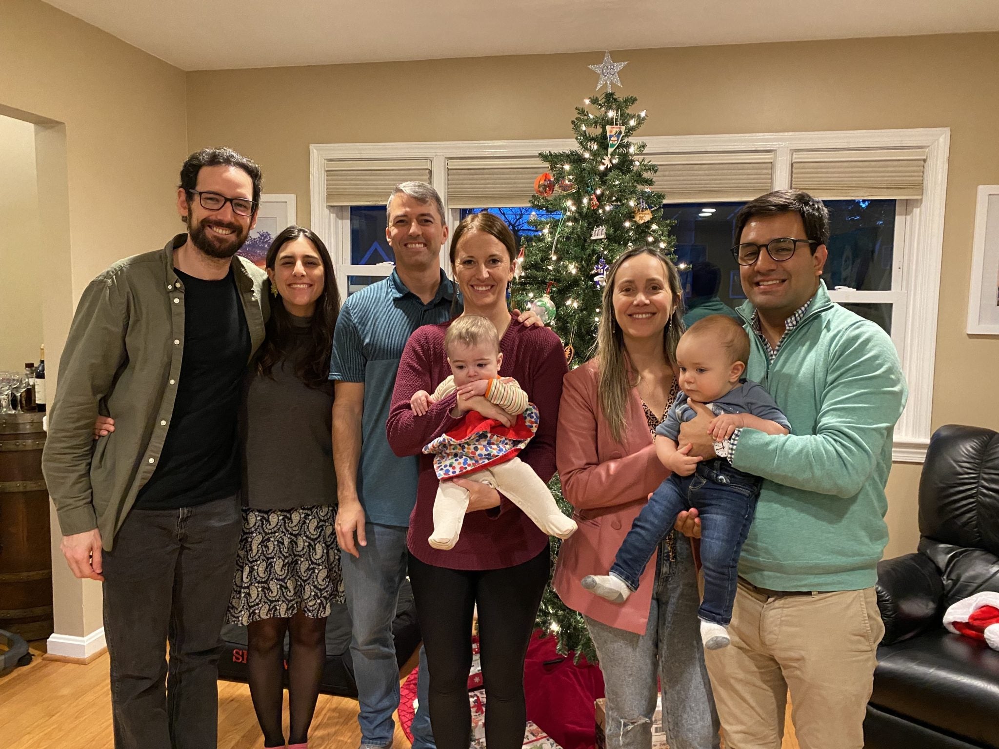 A group of student-parents and their babies in a home with a Christmas tree.