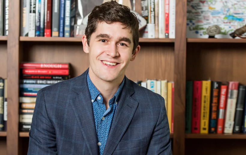 Headshot of Charlie Goodyear in front of a shelf full of books