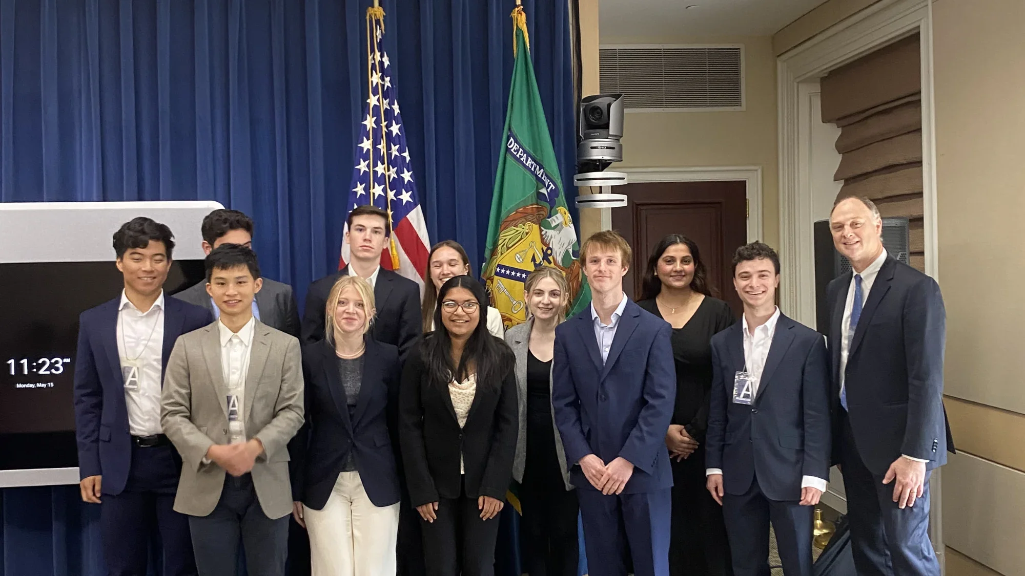 Image of students in business professional clothes in front of American flag.