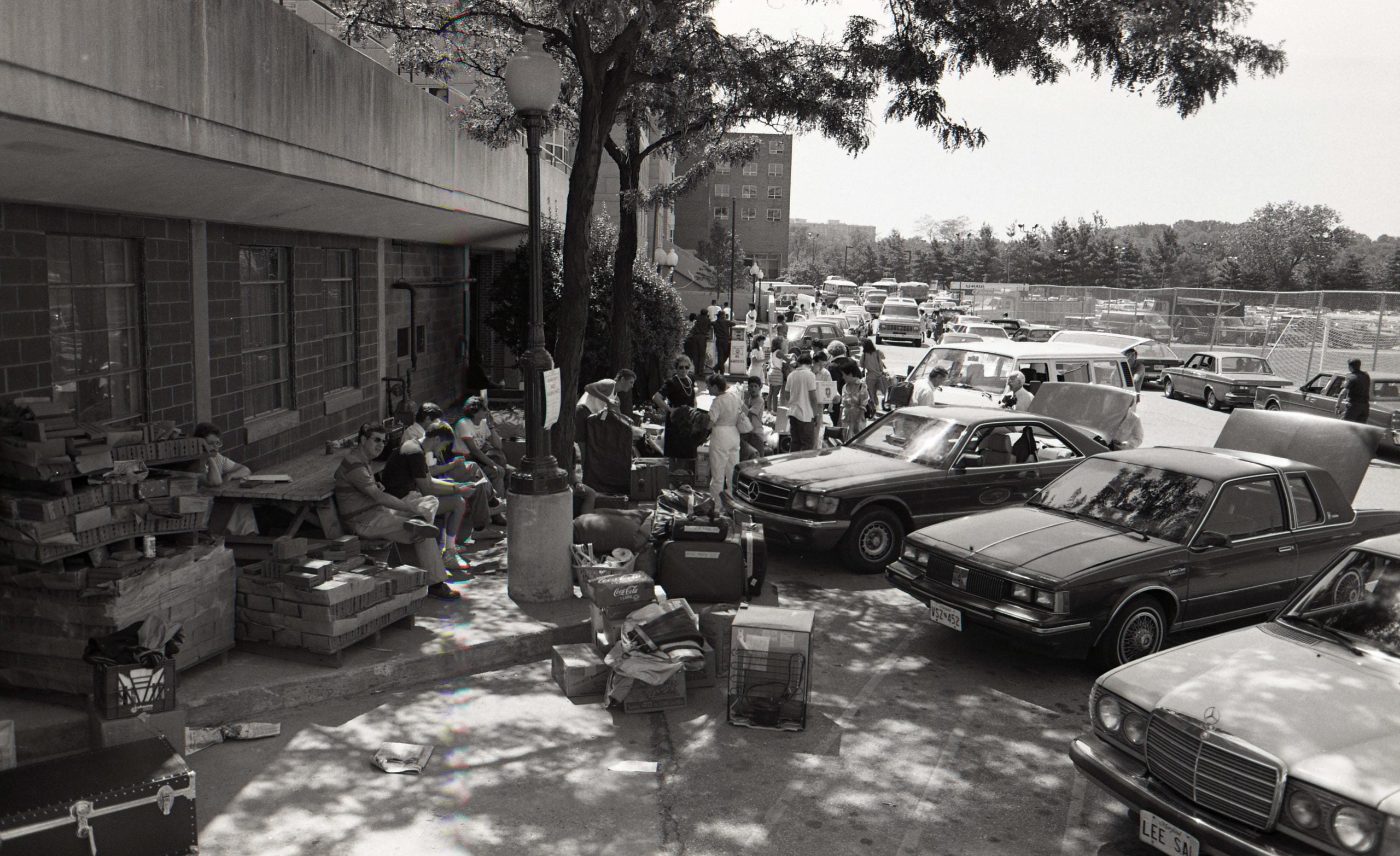 Black and white photo of cars by Harbin Hall with suitcases outside