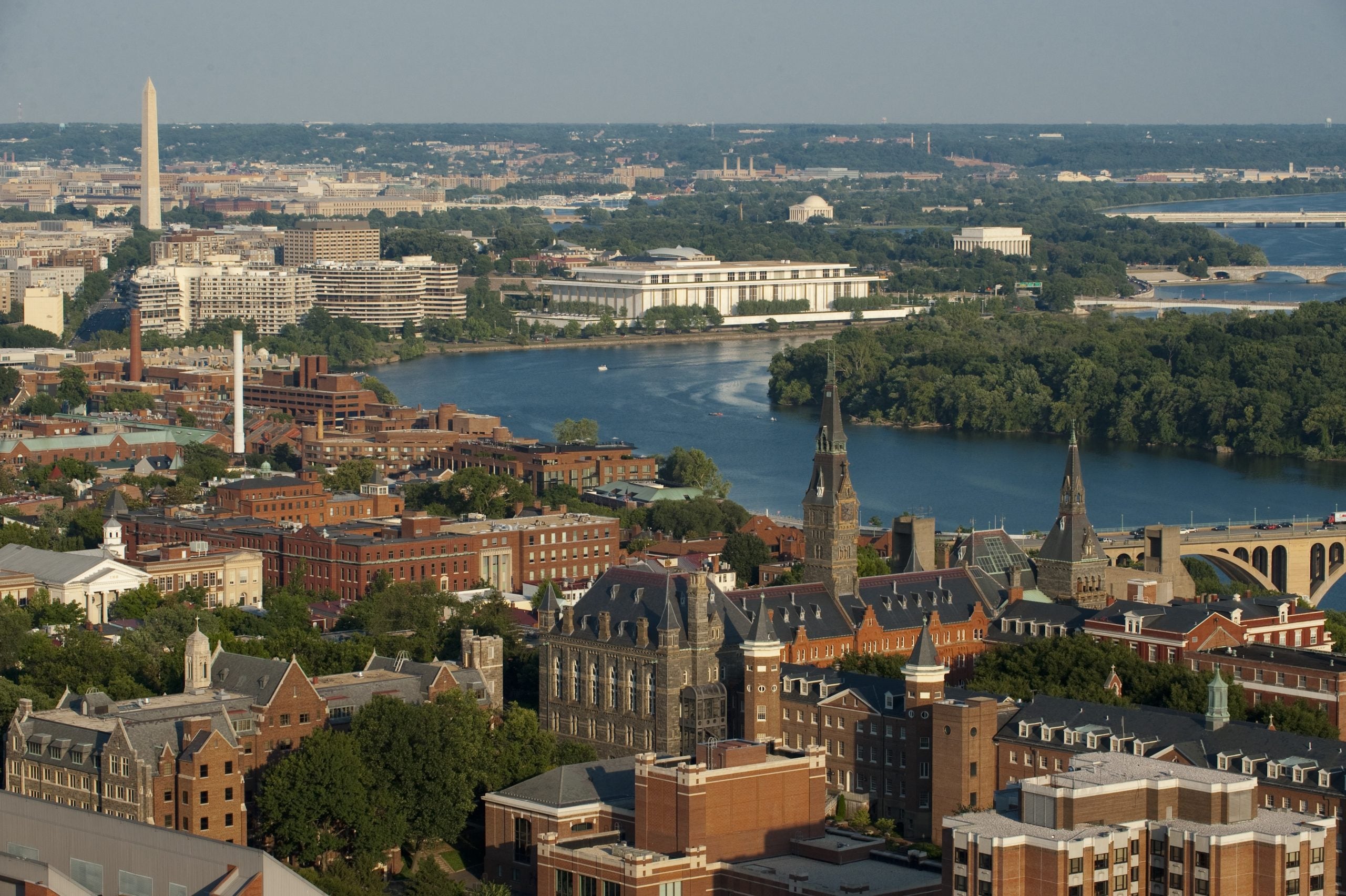 An aerial view of Georgetown's campus with the Washington monument and Potomac in the background.