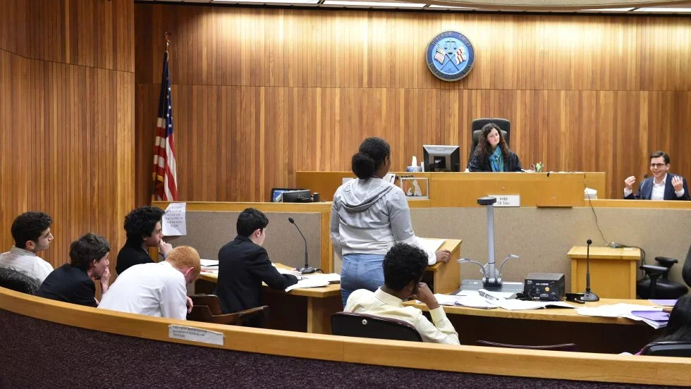 A high school student stands before a judge as part of the Georgetown Law program, Street Law.