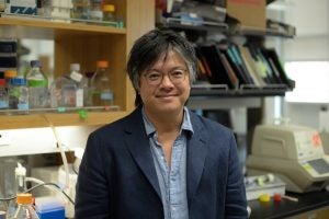 Portrait of Jeffrey Huang in his lab wearing a shirt and blazer