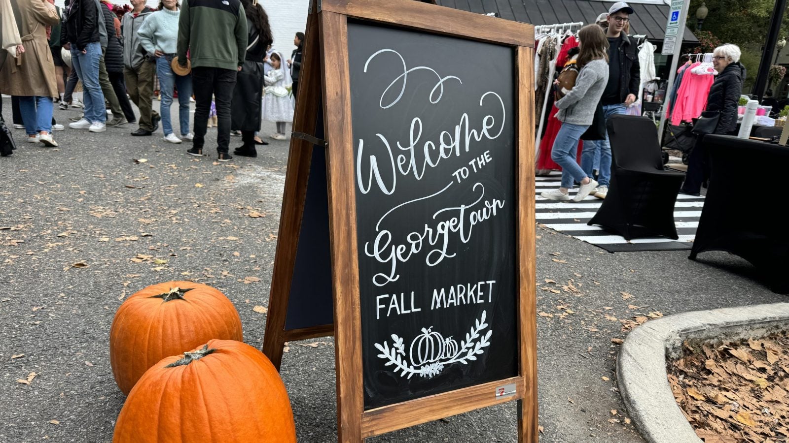 Pumpkins and chalkboard sign that reads &quot;Welcome to the Georgetown Fall Market&quot; in cursive