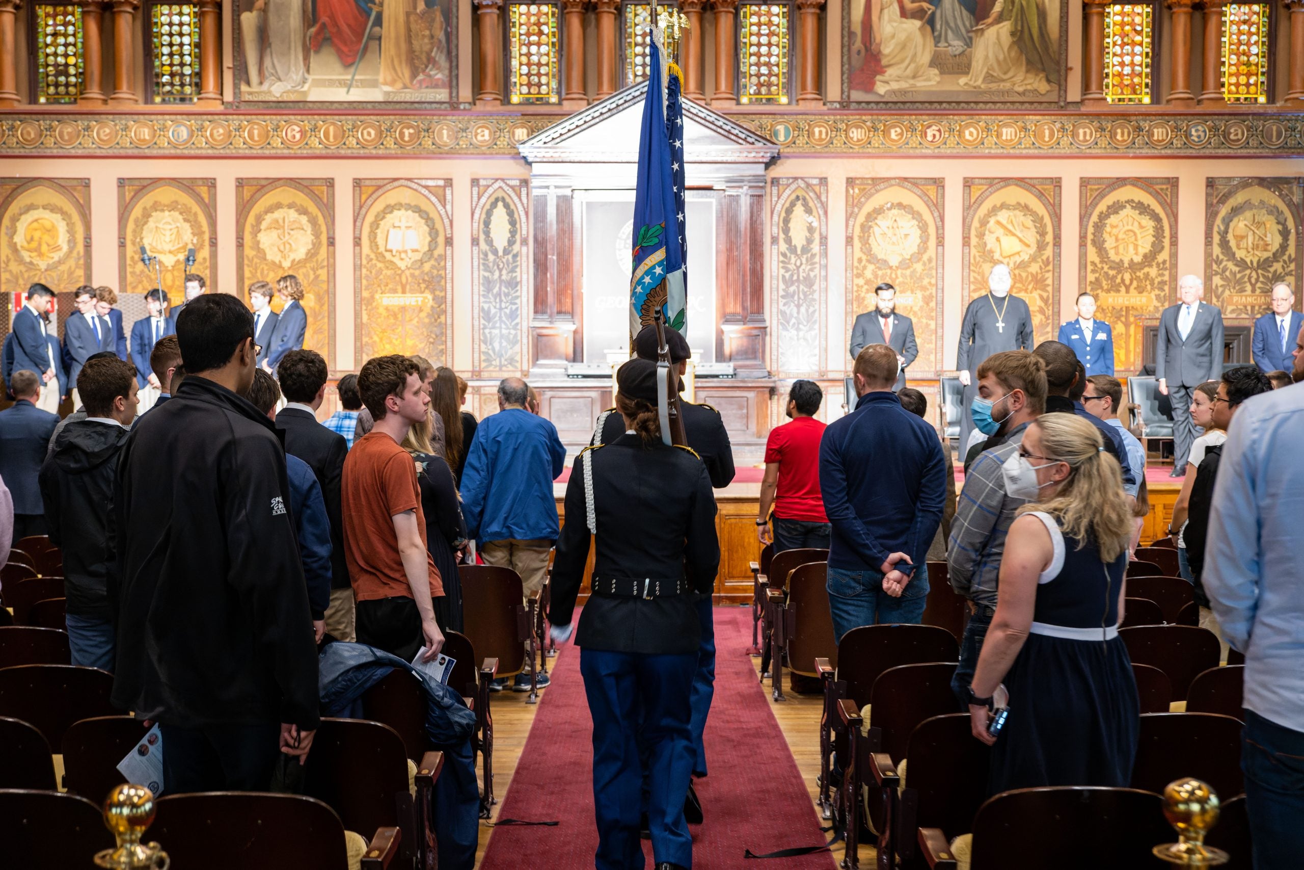 People in military dress waking down Gaston Hall with flags