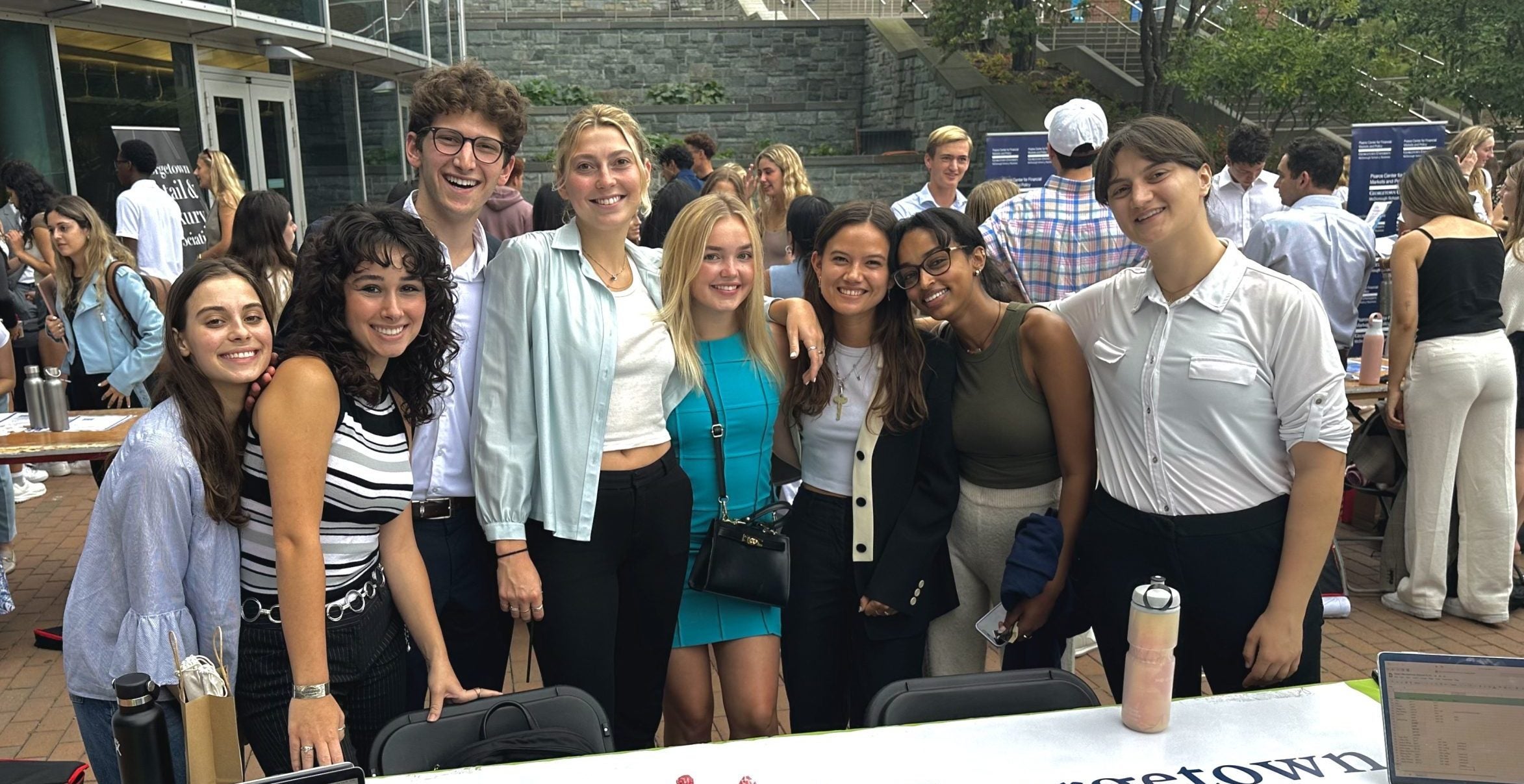 Students smile around a table adorned with a "Georgetown Eco-consultants" sign