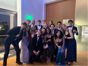 A large group of friends in formal attire pose and smile for a photo