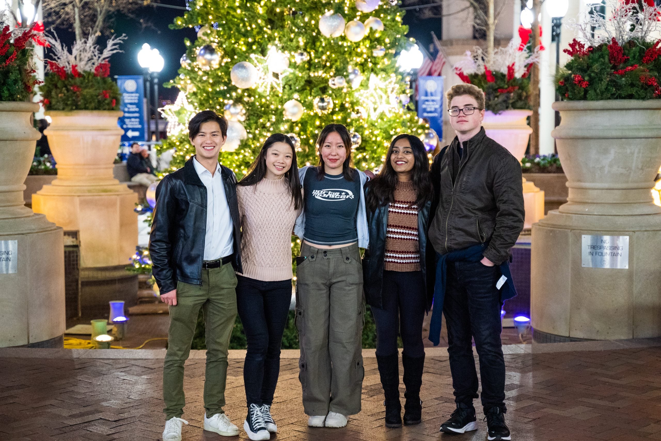 Bennie stands with his friends in front of a Christmas tree