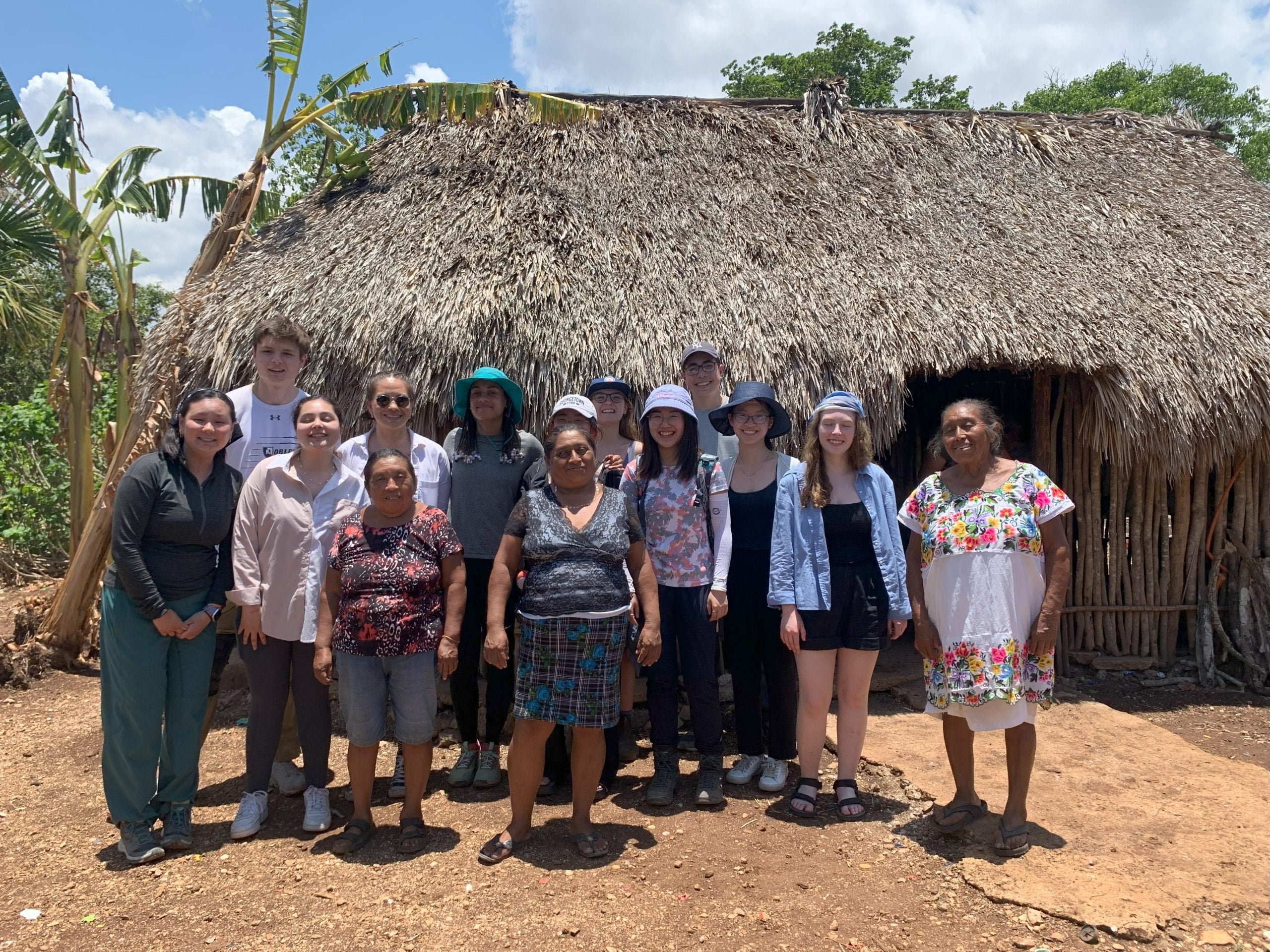 Group of students in front of a hut