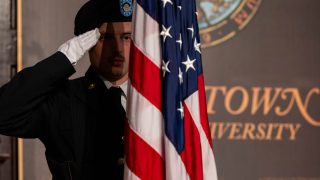 ROTC cadet saluting the American flag in Gaston Hall