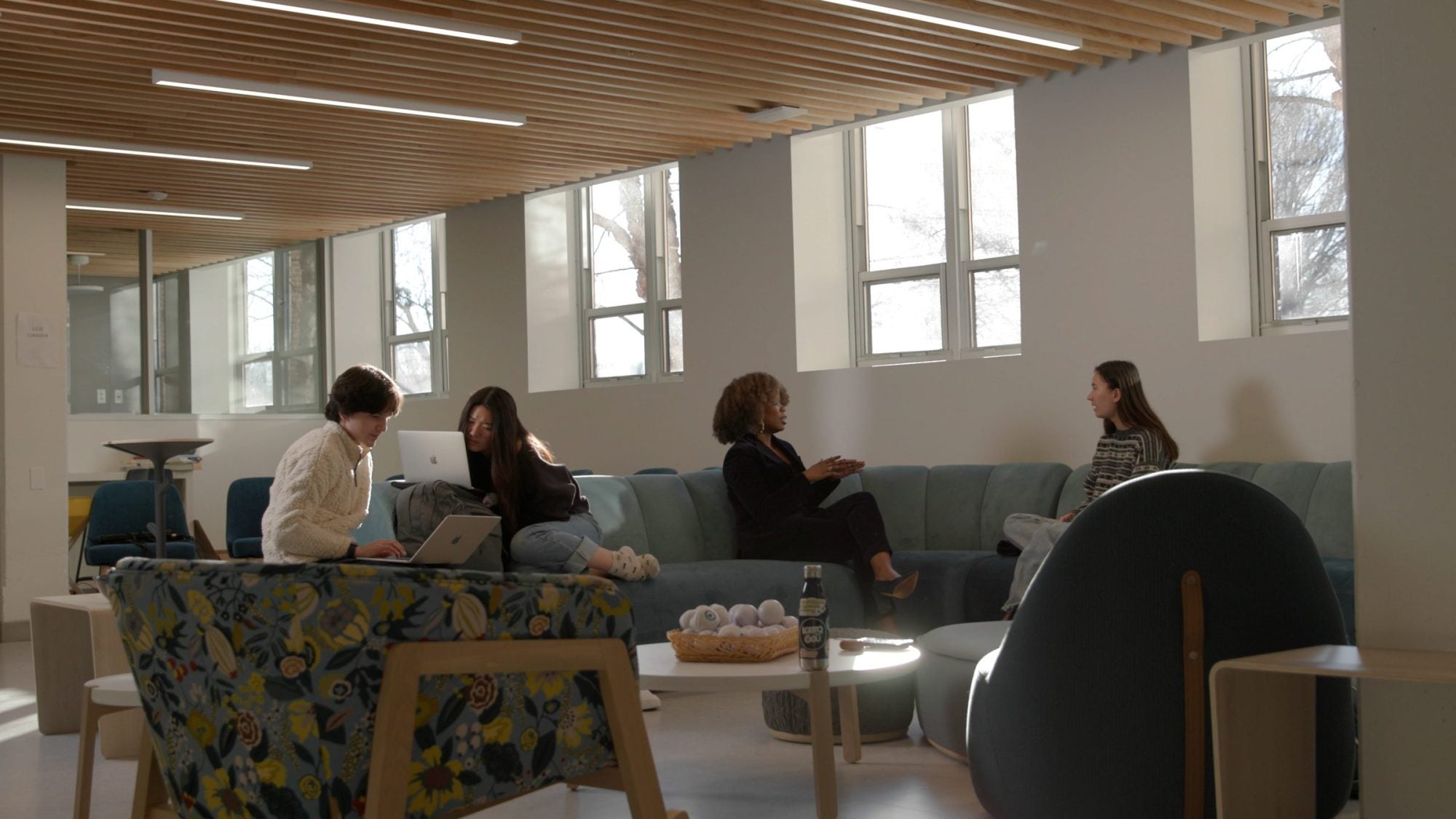 Several people sitting in a lounge space on chairs and couches