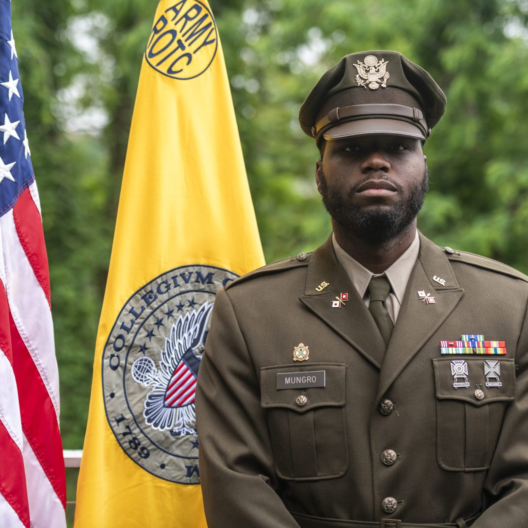 Lester Mungro standing at attention in front of the Army and US flag