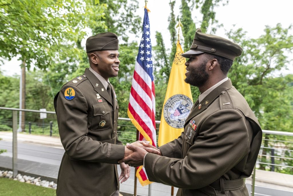 Lester Mungro shaking hands with Maj. Darius Hinton, both in Army dress uniforms.