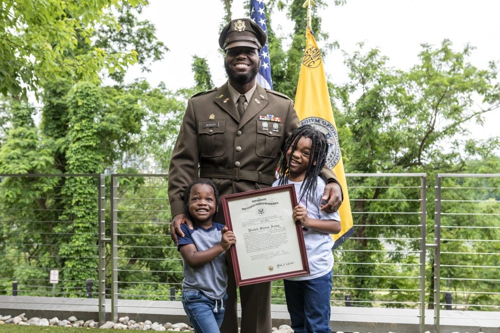 Lester Mungro with his two kids holding his certificate for earning his officer's commission