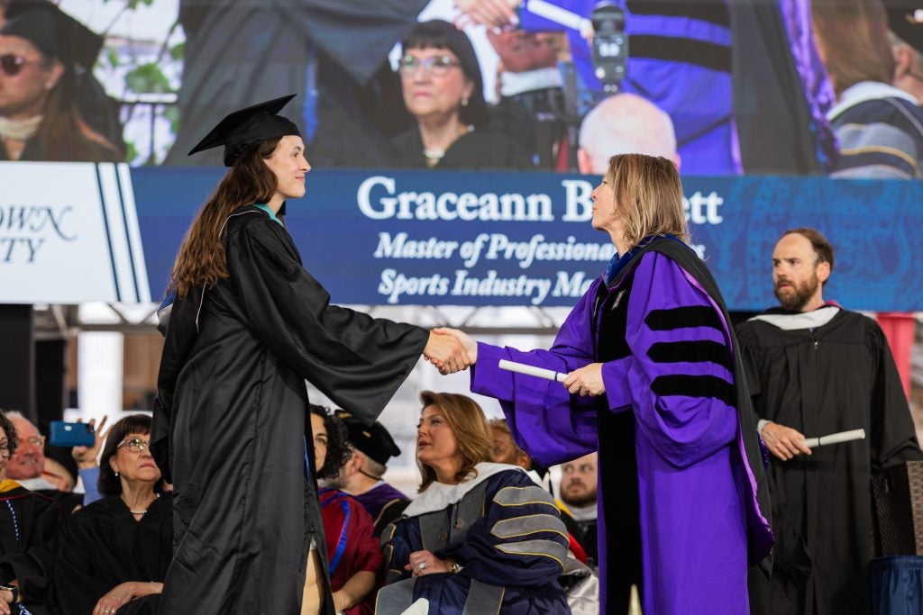 Graceann Bennett shakes the hand of a professor as she graduates from the School of Continuing Studies.