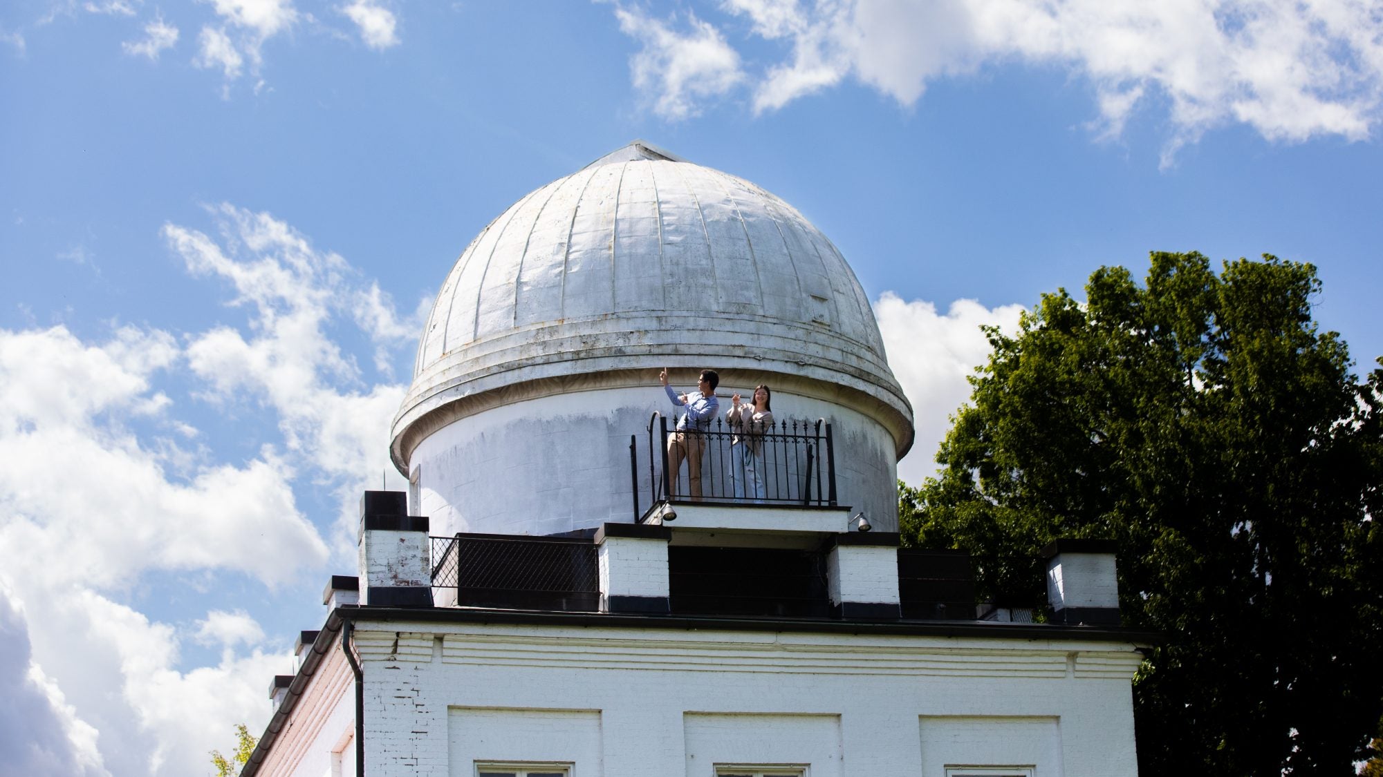 Two students on top of the Heyden Observatory dome on a sunny day