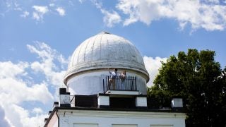 Two students on top of the Heyden Observatory dome on a sunny day