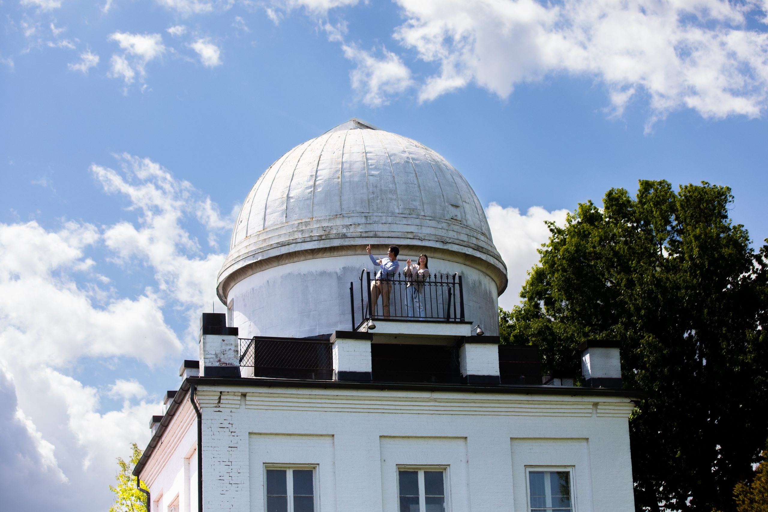 Two students on top of the Heyden Observatory dome on a sunny day