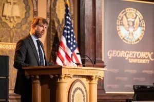 Adam Rothman speaking at a podium in Gaston Hall