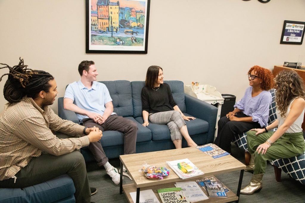 A group of law students and a career counselor sit in chairs and on a couch in a career services office