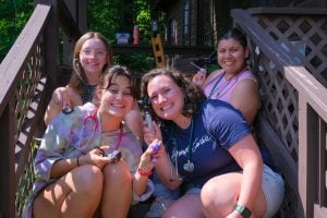 Four young women sitting on stairs outside holding medical equipment