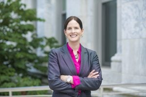 Laura DeNardis portrait. Laura is wearing a grey suit with a pink shirt