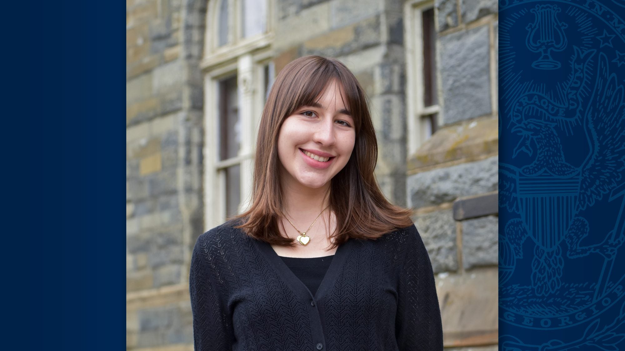 A headshot of Georgetown alumna Neval Mulaomerovic, who wears black and stands in front of a stone wall.