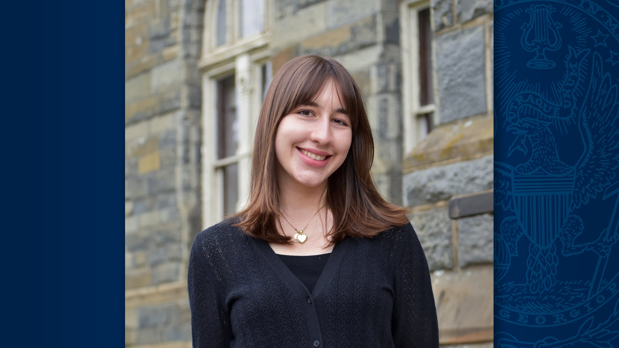 A headshot of Georgetown alumna Neval Mulaomerovic, who wears black and stands in front of a stone wall.