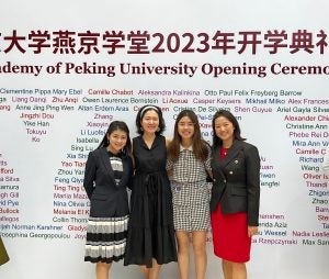Four Georgetown graduates and Yenching scholars stand in front of a sign welcoming them to the Yenching Academy opening ceremony.