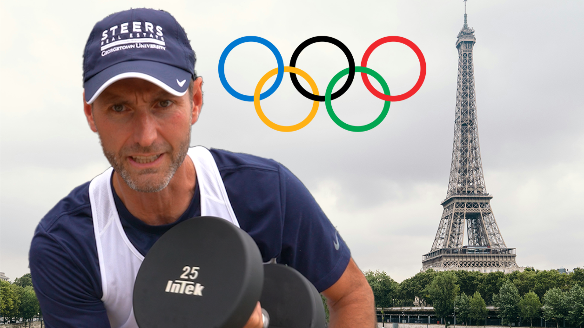 A man wearing a hat and a jersey lifts a weight with the Eiffel Tower behind him.