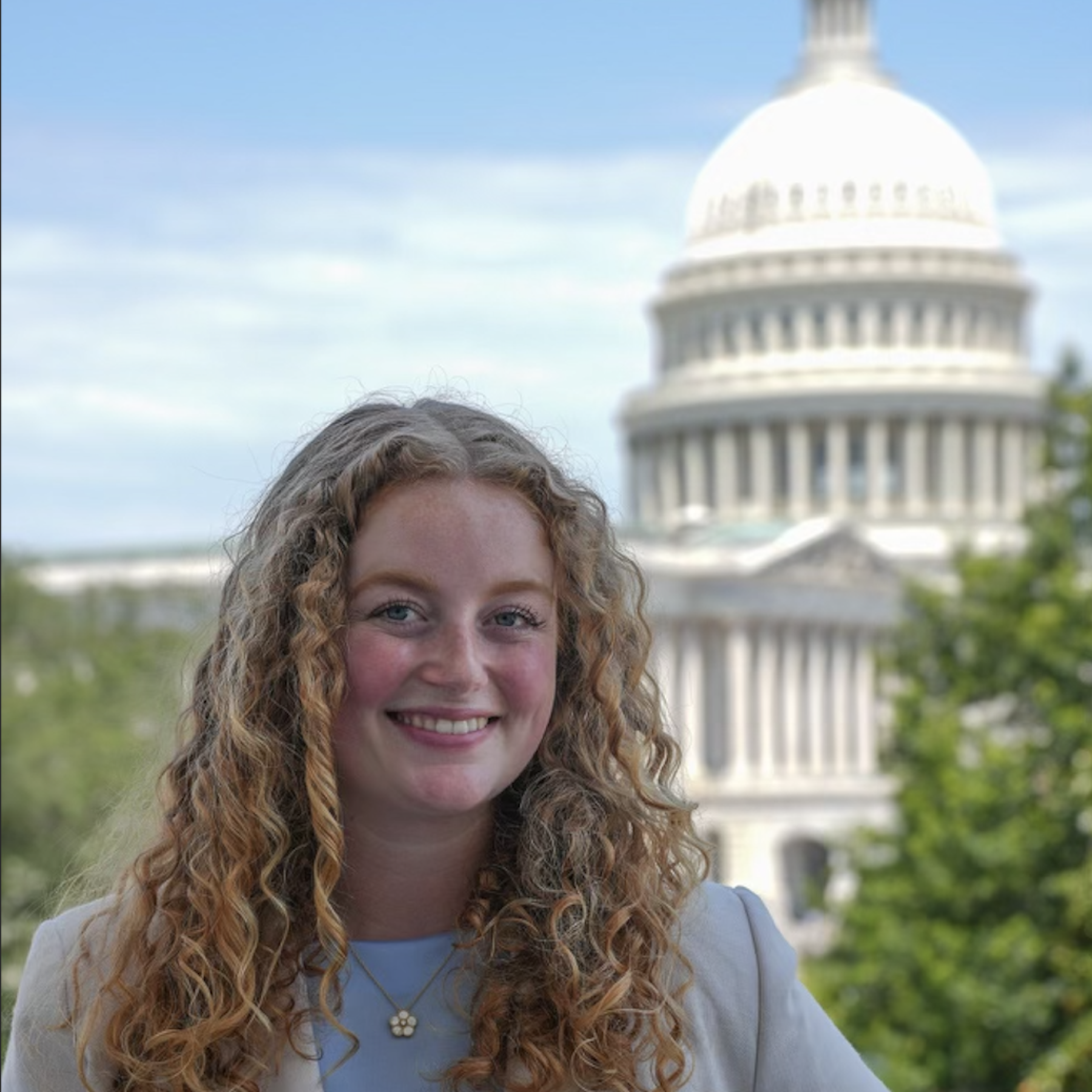 Maddie Davis in professional attire with the US Capitol in the background