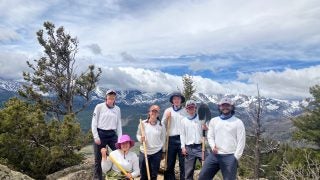 Six people in white shirts standing on top of a mountain on a cloudy day