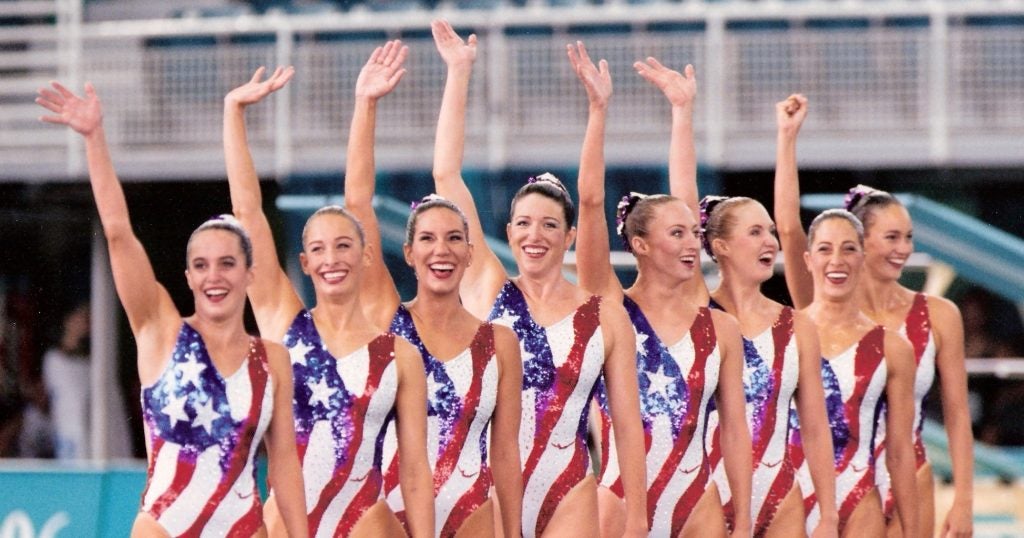 A group of American women wearing U.S. flag swimsuits wave during the 1996 Olympics.